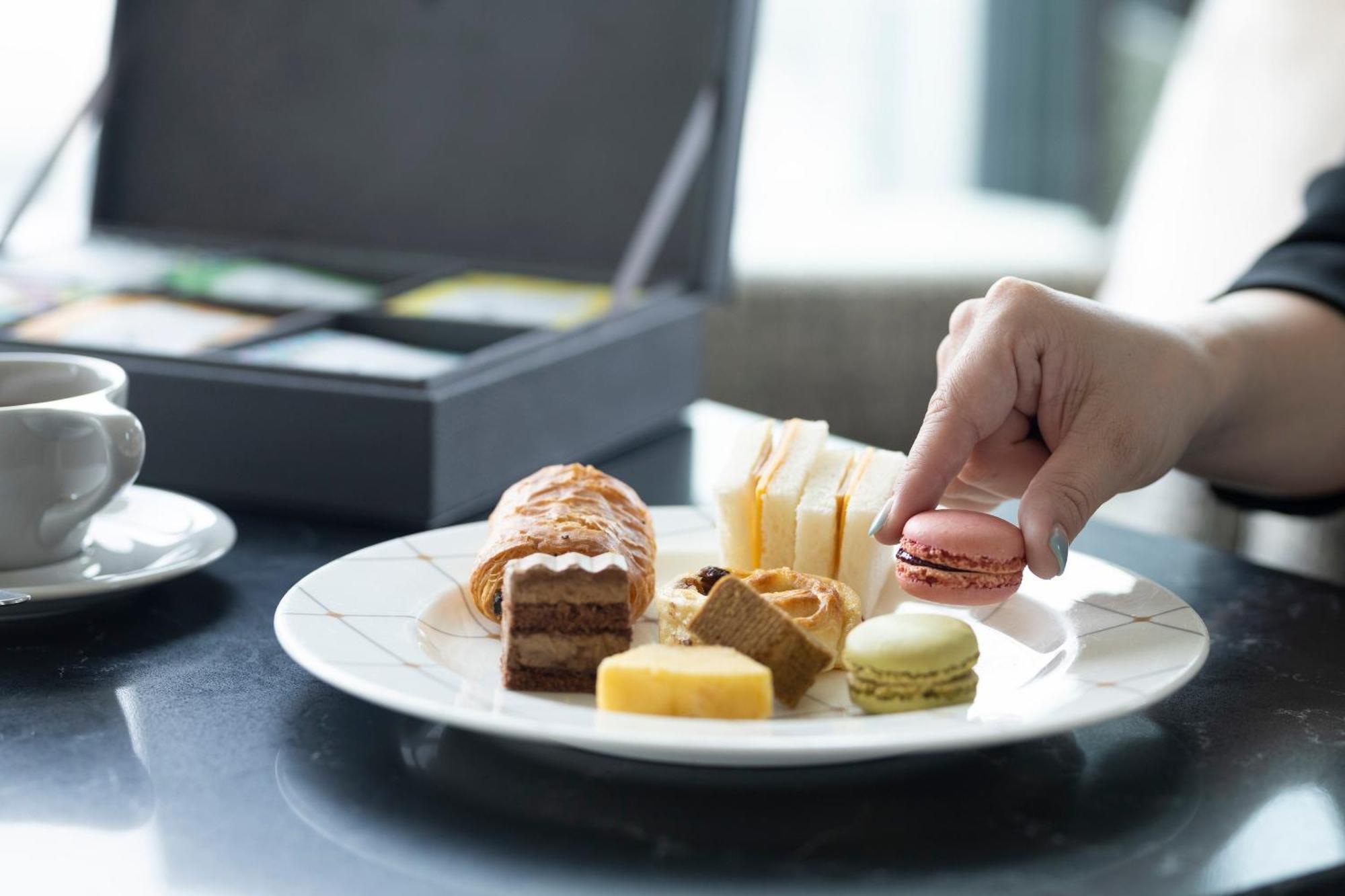 The Royal Park Hotel Iconic Osaka Midosuji Exterior photo A woman eating a plate of petit fours
